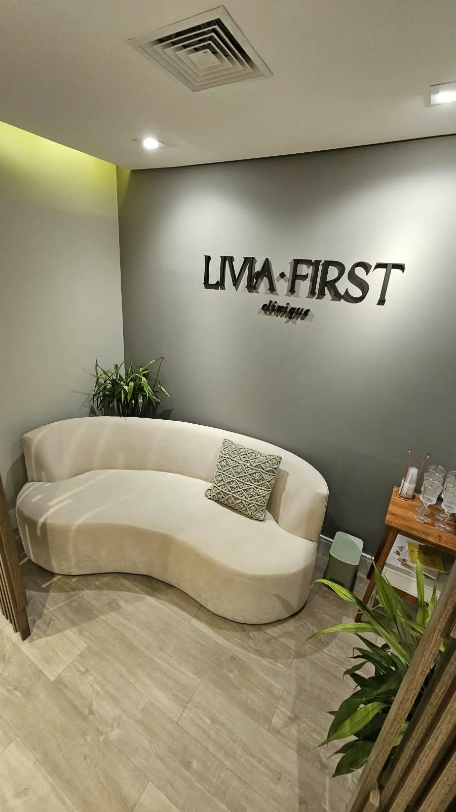 Recepção do estúdio Livia First, com sofá claro e a marca na parede